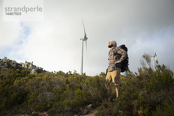 Spanien  Andalusien  Tarifa  Mann auf einer Wanderung mit Windkraftanlage im Hintergrund