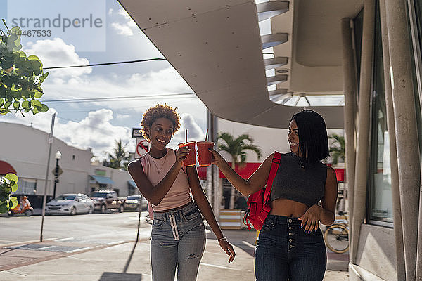 USA  Florida  Miami Beach  zwei glückliche Freundinnen bei einem Erfrischungsgetränk in der Stadt