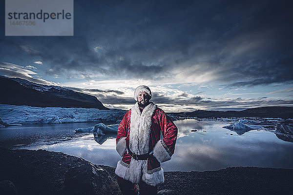 Island  Porträt eines als Weihnachtsmann verkleideten Mannes  der an einem Gletscher steht