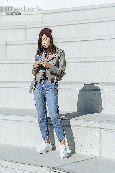 Junge Frau benutzt Smartphone im Freien