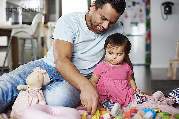 Vater und kleines Mädchen spielen zu Hause mit Bauklötzen