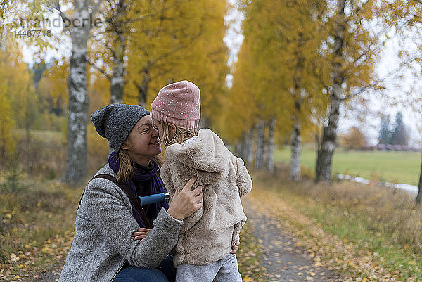 Mutter und kleine Tochter kuscheln im Herbst im Freien