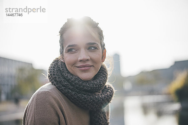 Porträt einer lächelnden Frau mit Schal im Gegenlicht