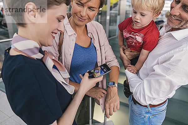 Mitarbeiter einer Fluggesellschaft scannt QR-Codes von Passagieren mit Smartwatch am Flughafen