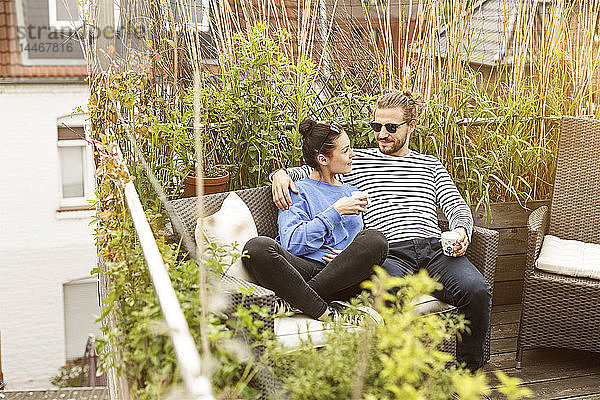 Junges Paar entspannt sich auf dem Balkon  auf der Couch sitzend