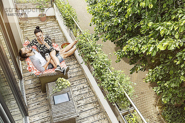 Liebespaar sitzt im Sommer auf dem Balkon und unterhält sich