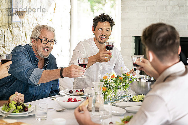 Glückliche Familie beim gemeinsamen Essen klirrende Weingläser