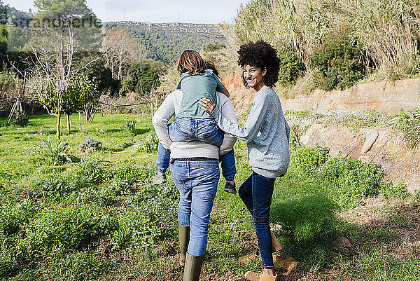 Glückliche Familie beim Spaziergang auf dem Land  Vater trägt Sohn huckepack