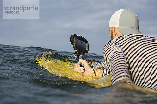 Indonesien  Bali  Mann mit wasserdichtem Smartphone im Meer