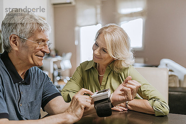 Lächelndes älteres Paar bei der Blutdruckmessung