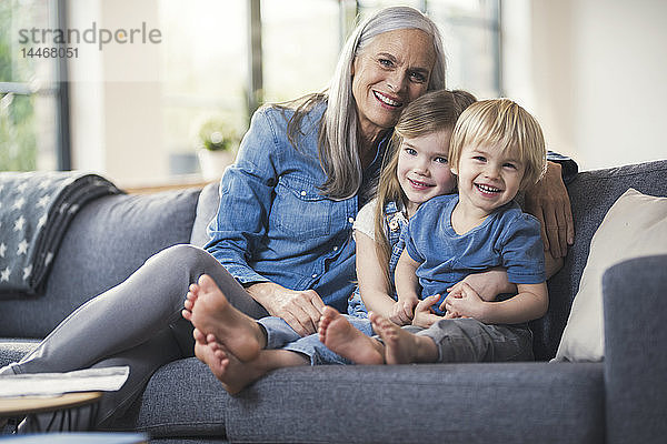 Großmutter sitzt mit ihren Enkelkindern auf der Couch