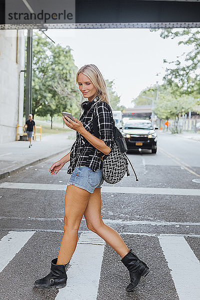 USA  New York City  Brooklyn  lächelnde junge Frau mit Handy auf der Straße