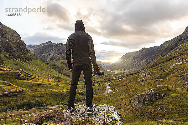 Großbritannien  Schottland  Mann mit Blick auf die Drei Schwestern von Glencoe Berge auf der linken Seite und die Straße A82 in der Mitte des Tals