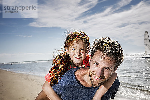 Niederlande  Zandvoort  Porträt eines lächelnden Vaters mit Tochter am Strand