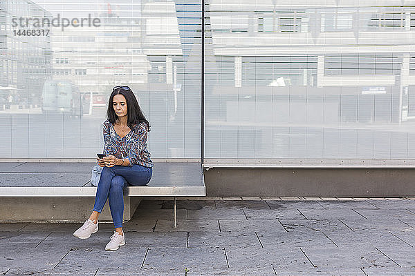 Reife Frau benutzt Smartphone im Freien