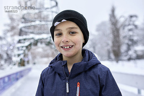 Porträt eines Jungen mit Wollmütze  der sich beim Eislaufen auf der Eisbahn amüsiert