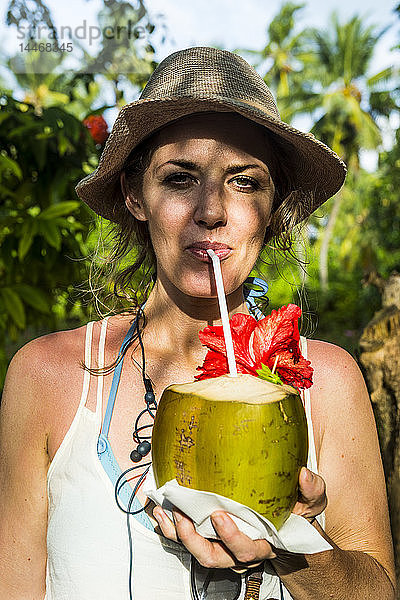 Malediven  Ari Atoll  Nalaguraidhoo  Sonneninsel  Porträt einer Frau  die frisches Kokosnusswasser trinkt