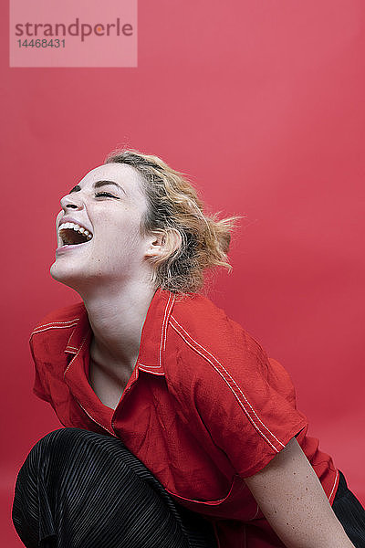 Lachende junge Frau liniert vor rotem Hintergrund
