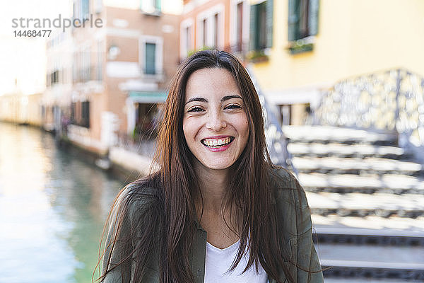 Italien  Venedig  Porträt einer lachenden jungen Frau in der Stadt mit Kanal im Hintergrund
