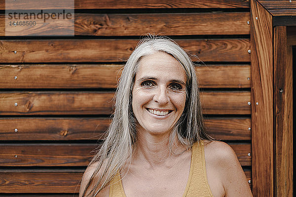 Porträt einer lächelnden reifen Frau vor einer Holzfassade