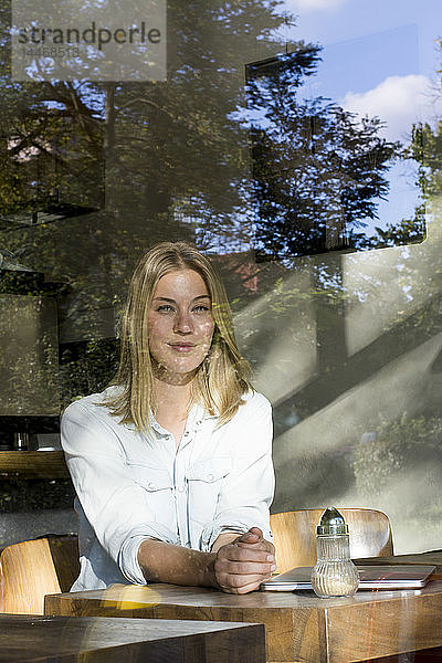 Porträt einer blonden Frau in einem Cafe  die aus dem Fenster schaut