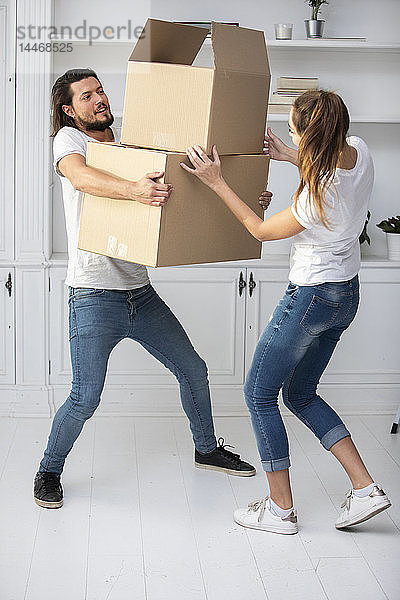 Paar mit Freundin trägt Pappkartons im neuen Zuhause