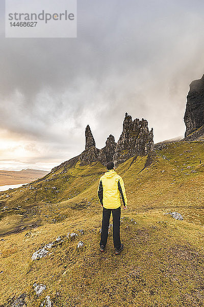 Großbritannien  Schottland  Isle of Skye  Mann wandert an einem bewölkten Tag zum Old Man of Storr