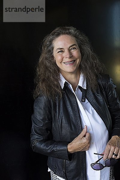 Porträt einer lächelnden reifen Frau in schwarzer Lederjacke