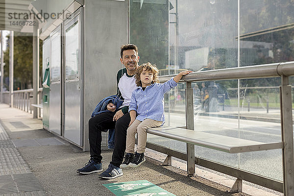 Vater und Sohn sitzen an der Straßenbahnhaltestelle in der Stadt