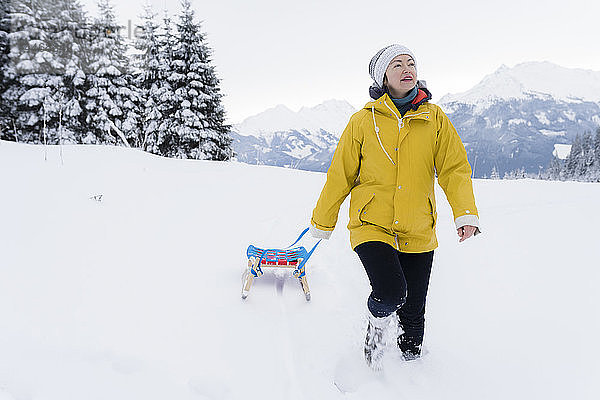 Österreich  Tirol  Thurn  reife Frau beim Schlittenziehen in schneebedeckter Landschaft