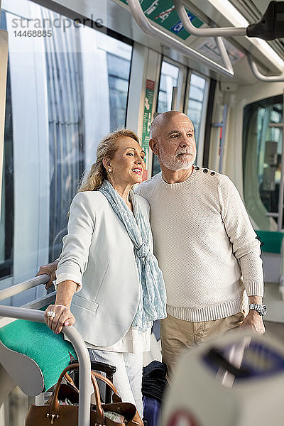Älteres Ehepaar steht in einer Straßenbahn und sieht sich um