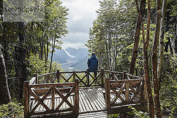 Chile  Chaiten  Parque Pumalin  Mann sitzt auf der Aussichtsplattform und schaut auf den Gletscher