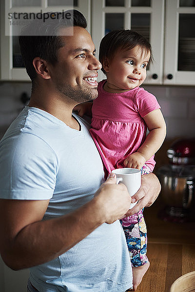 Lächelnder Vater hält Mädchen zu Hause in der Küche