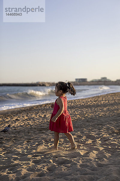 Süßes kleines Mädchen steht am Strand und schaut auf das Meer