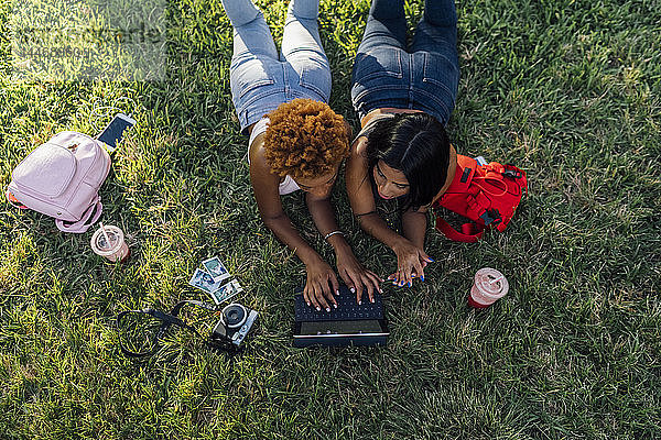 Zwei Freundinnen entspannen sich mit einer Tablette in einem Park