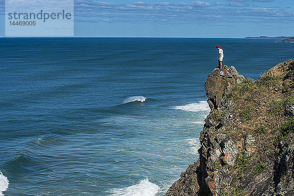 Australien  Queensland  Byron Bay  Mann auf einem Felsen stehend  Klippe bei Cape Byron