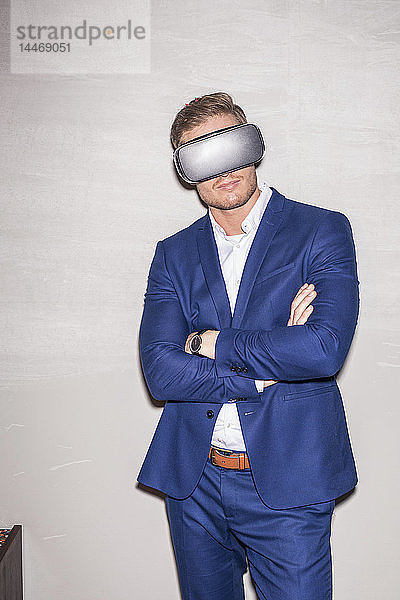 Junger Mann im blauen Anzug mit Virtual-Reality-Brille