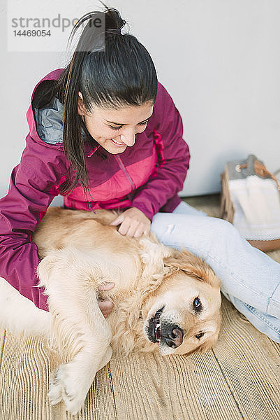 Glückliche junge Frau streichelt und spielt mit ihrem Golden Retriever-Hund