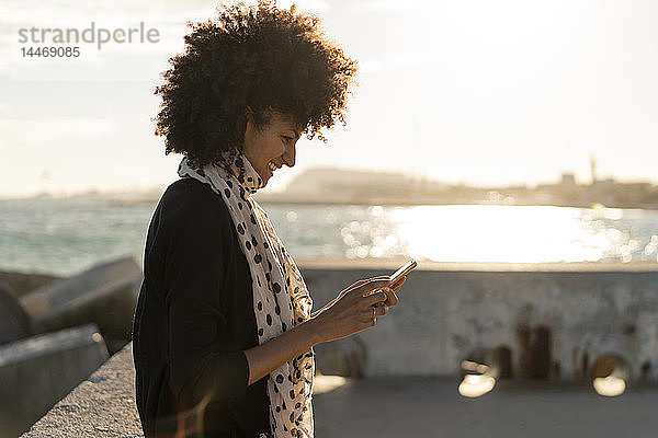 Lächelnde Frau mit Smartphone am Meer