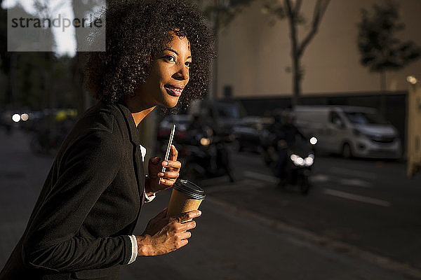 Porträt einer Geschäftsfrau mit Kaffee zum Mitnehmen und Handy in der Abenddämmerung wartend