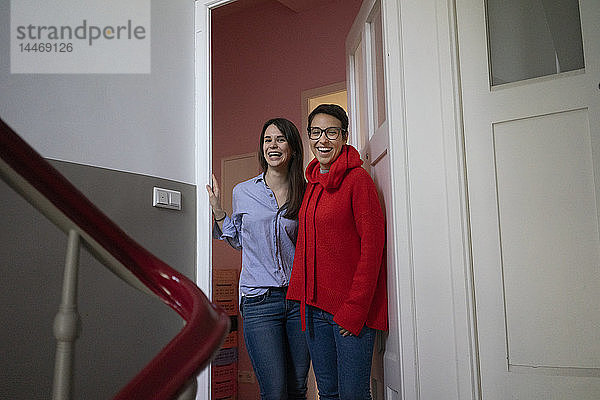 Zwei Freundinnen zu Hause stehen im Türkasten  mit den Armen um den Hals