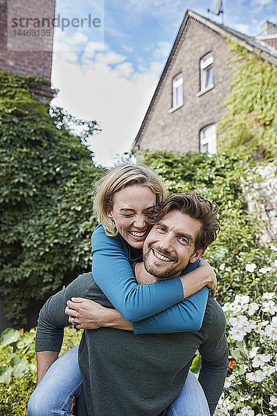 Porträt eines glücklichen Paares im Garten ihres Hauses