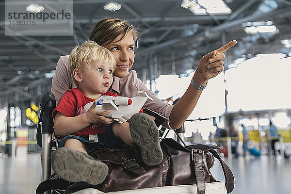 Deutschland  Köln  Porträt von Mutter und kleinem Sohn mit Gepäckwagen im Flughafenterminal
