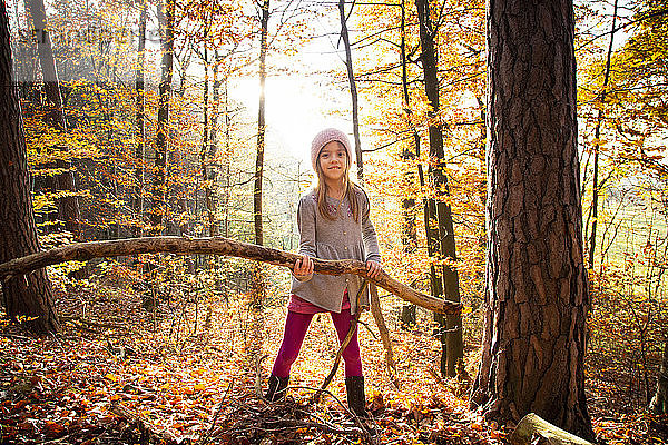 Junges Mädchen hält Zweig im Herbstwald