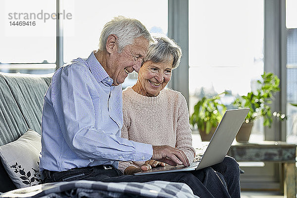 Älteres Ehepaar sitzt zusammen auf der Couch mit Laptop