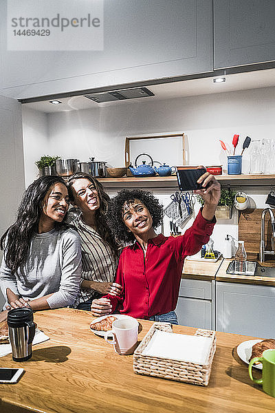Drei glückliche Frauen posieren für ein Selfie bei Tisch