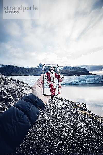 Island  als Weihnachtsmann verkleideter Mann kommt aus einem Handy