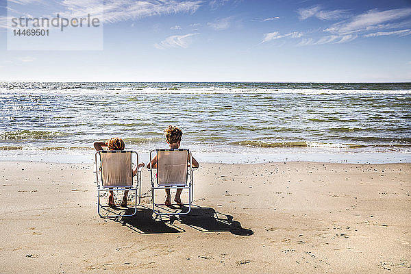 Niederlande  Zandvoort  Junge und Mädchen sitzen auf Stühlen am Strand