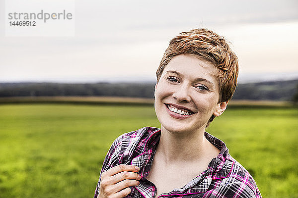 Porträt einer lächelnden Frau im Pyjama in ländlicher Landschaft