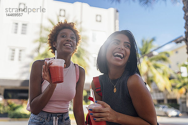 USA  Florida  Miami Beach  zwei glückliche Freundinnen bei einem Erfrischungsgetränk in der Stadt